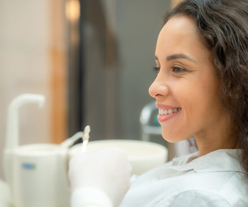 Beautiful woman checking teeth after curing teeth in dental clinic,Woman looking at mirror with smile.
