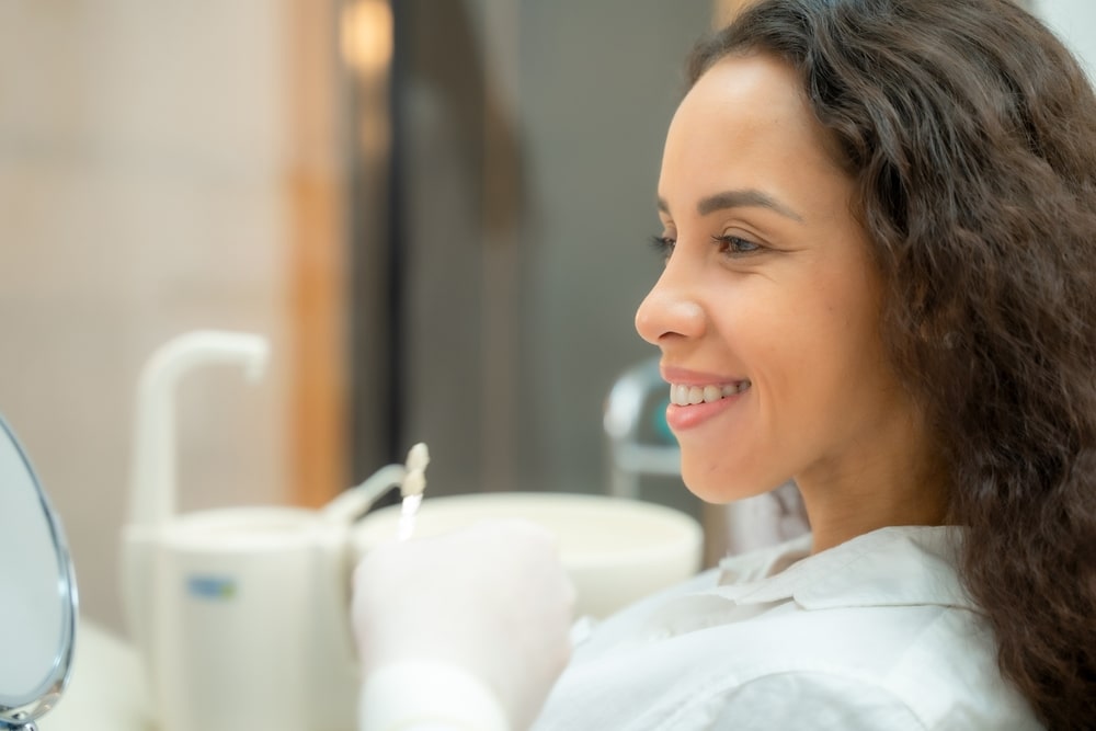 Beautiful woman checking teeth after curing teeth in dental clinic,Woman looking at mirror with smile.