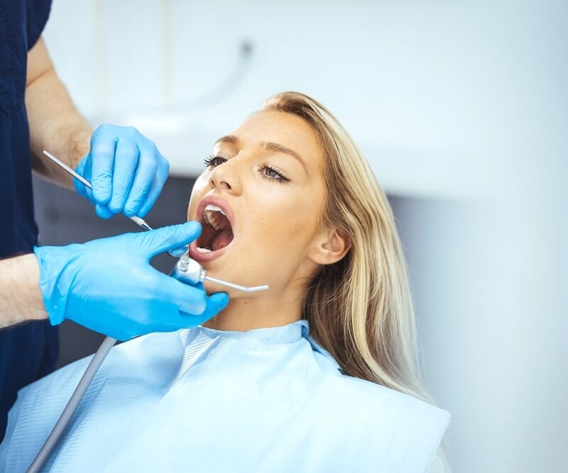 Closeup shot professional dentist with protective surgical mask, doing check up of patient