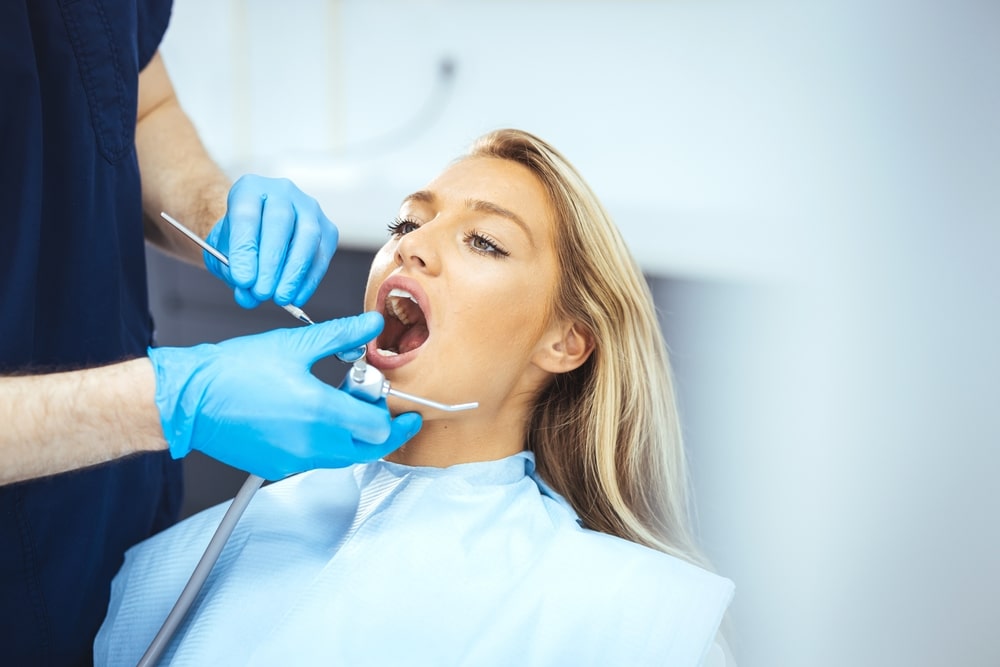 Closeup shot professional dentist with protective surgical mask, doing check up of patient